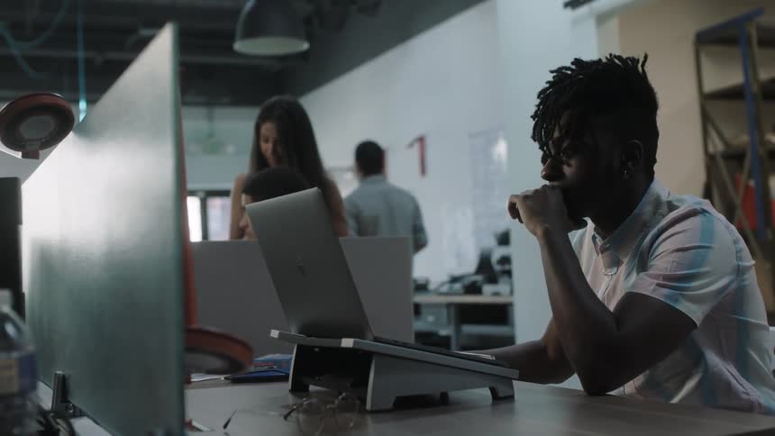 A man is using a laptop as he works in an office