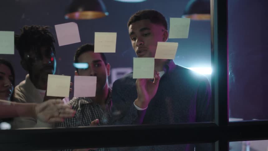 A group of people read post it notes on a window