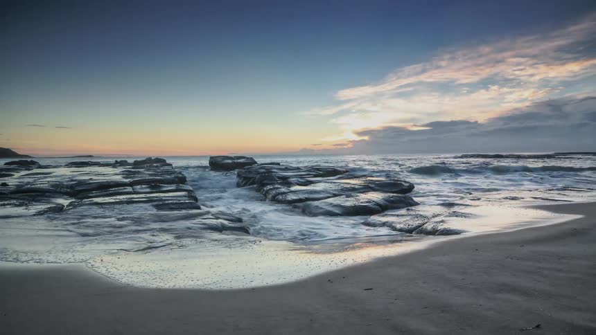 Water flowing onto a sandy beach at sunset