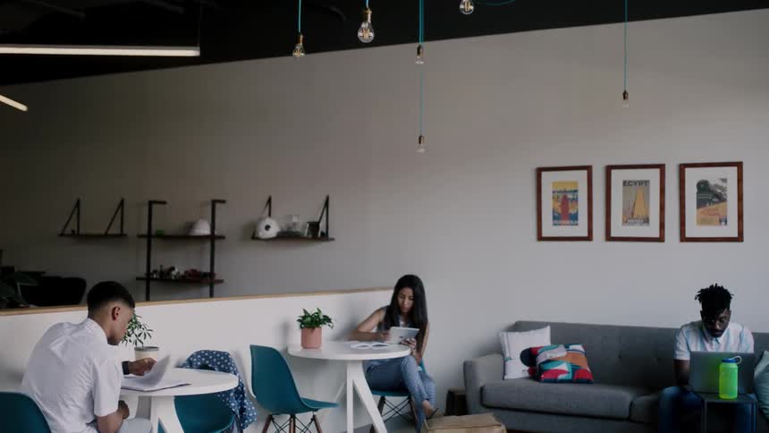 A group of people sit at tables and on a couch