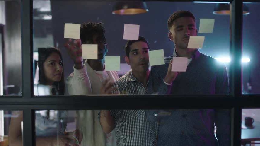 A group of people are looking at sticky notes on a window