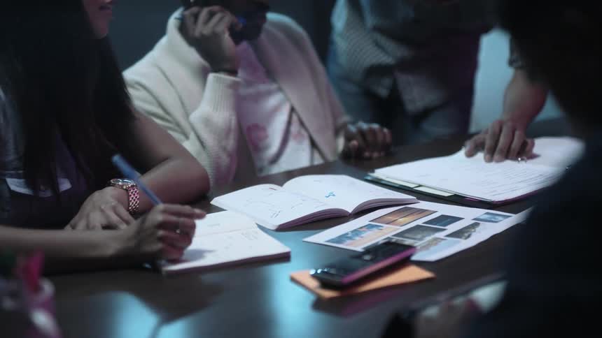 People in an office gathered at a table discuss a project
