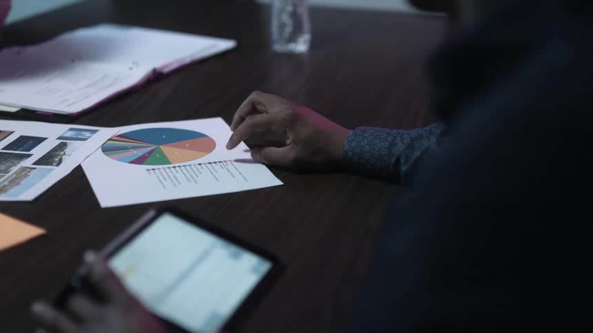 People sitting at a desk looking at a graph on a piece of paper