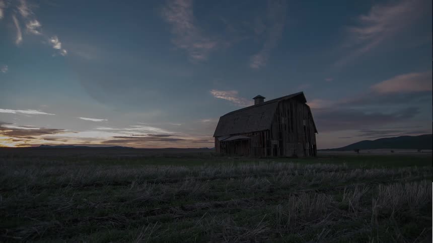 Time lapse of a lone barn sitting on a large field