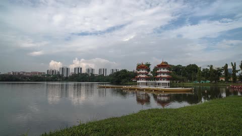 A body of water with rowboats floating nearby and high-rise buildings in the background