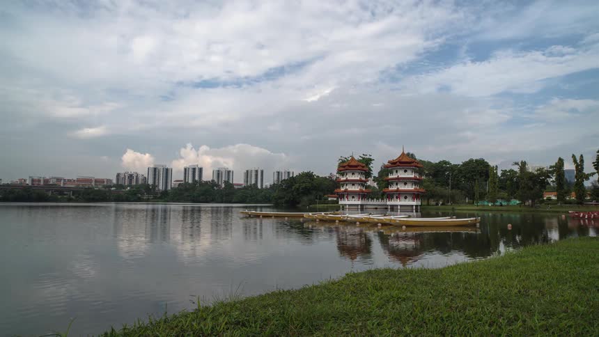 A body of water with rowboats floating nearby and high-rise buildings in the background