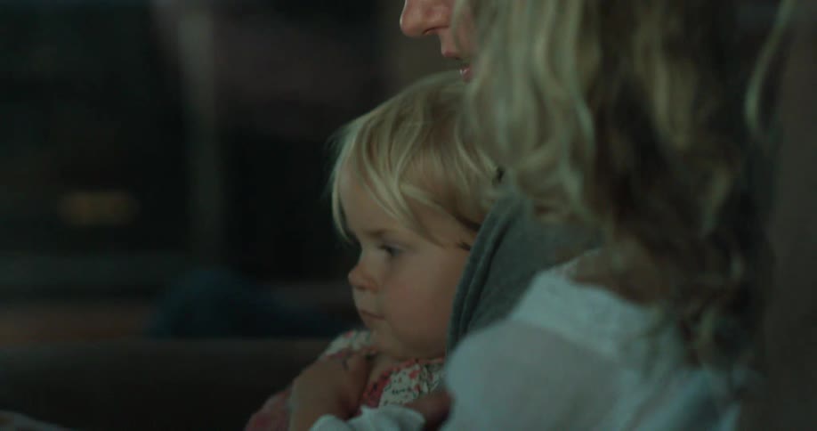 A woman reads a book to a young girl on her lap