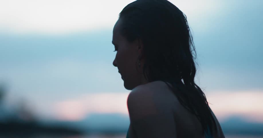 A woman swims in a lake at sunset