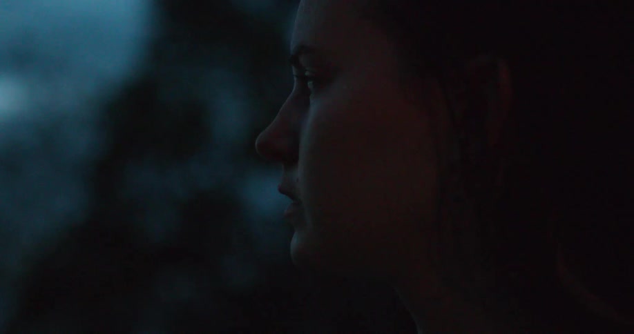 A young girl looks outside at night