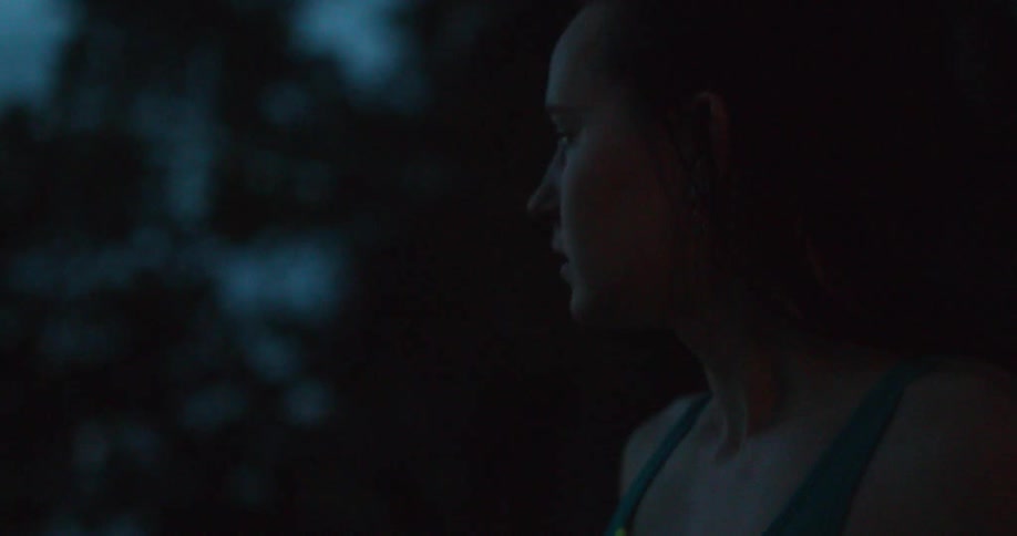 A woman looks at a lake at sunset