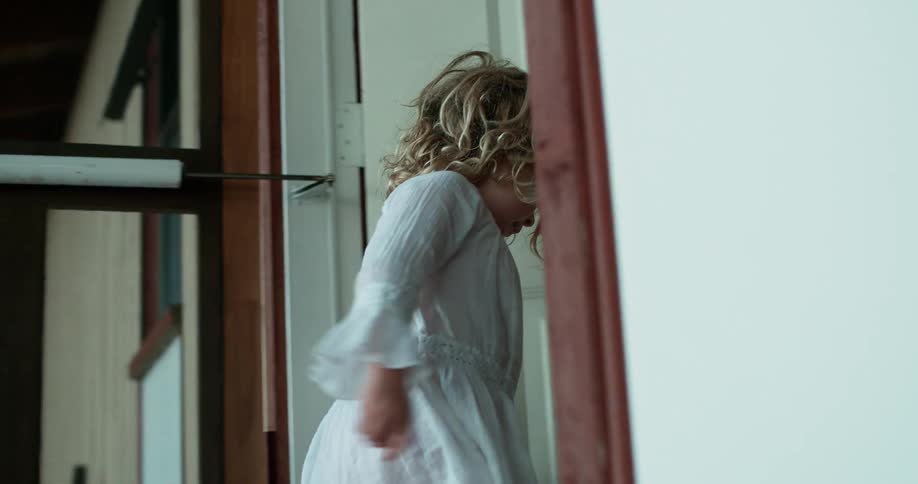 A young girl enters the front door of a house