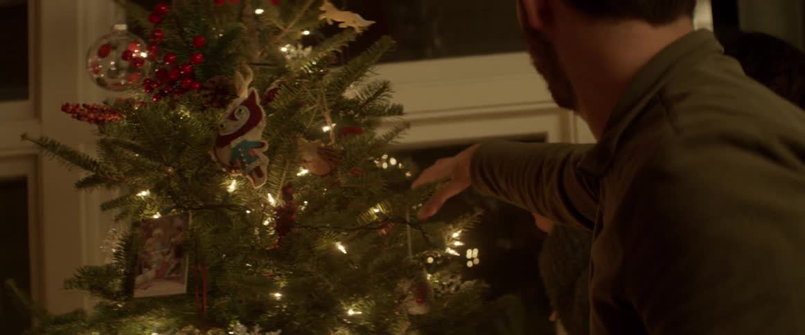 People hang ornaments on a christmas tree