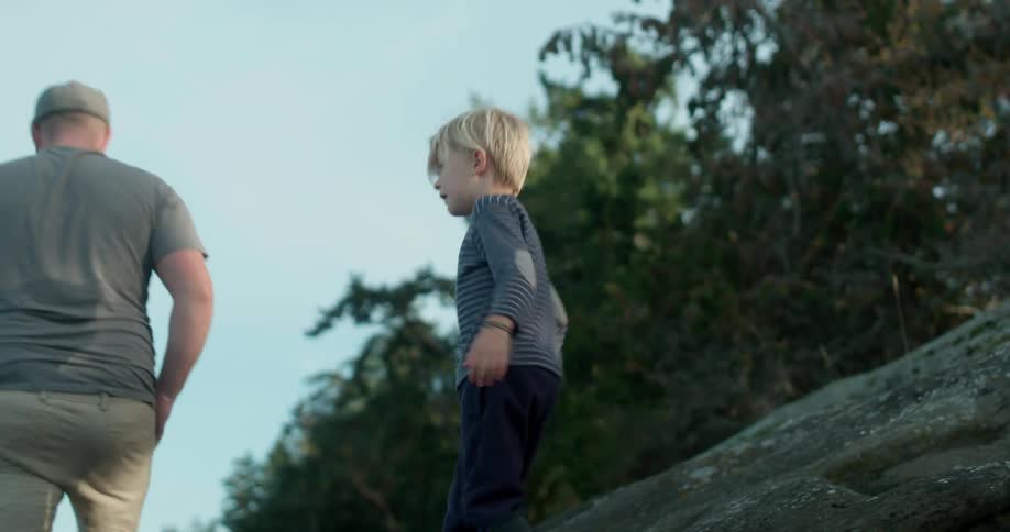A father and son walk on a lakeshore