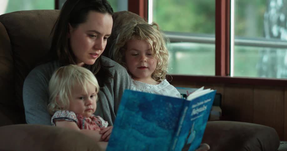 A woman reads a book with two children
