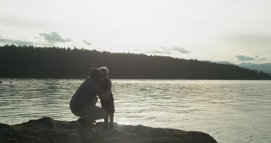 A father and son look out at a rippling lake