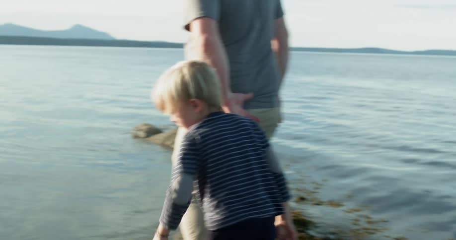 A man and his son walk on rocks to the water