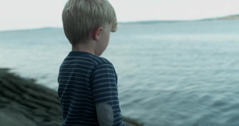 A young boy throws a branch into the water