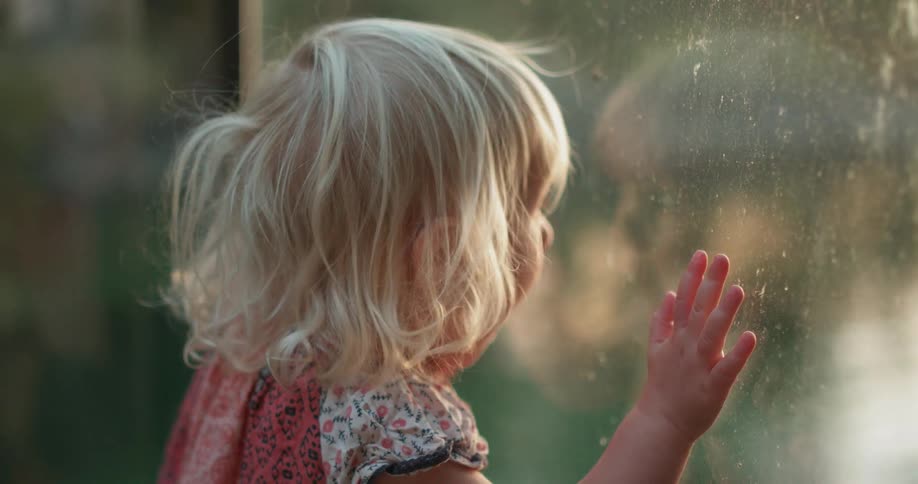 Child press hands against glass looking outside