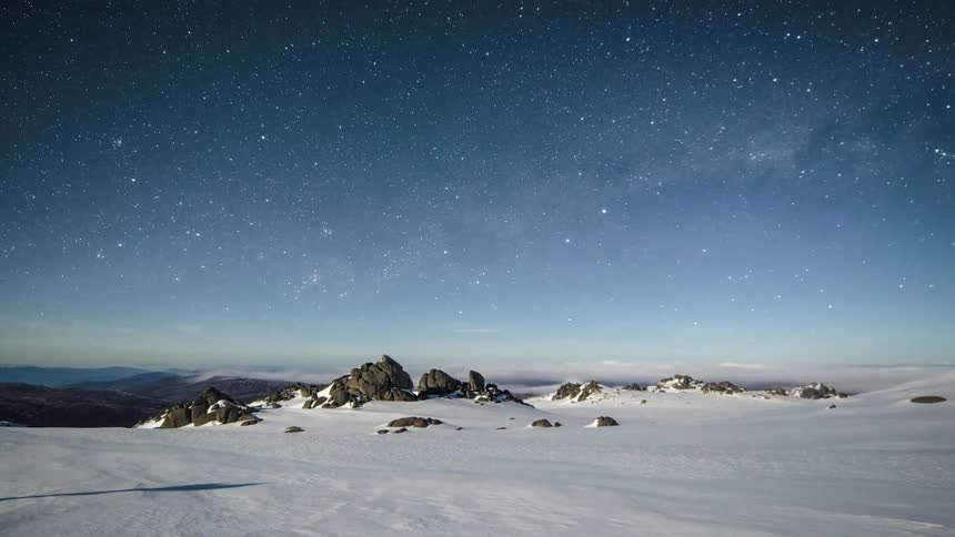 Time lapse view of rotating stars and clouds over a frozen tundra