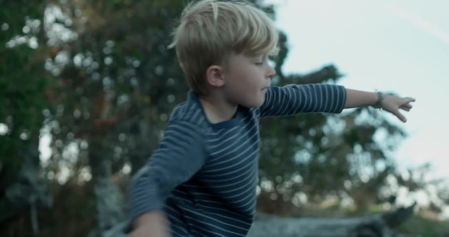 Young boy throws a piece of driftwood