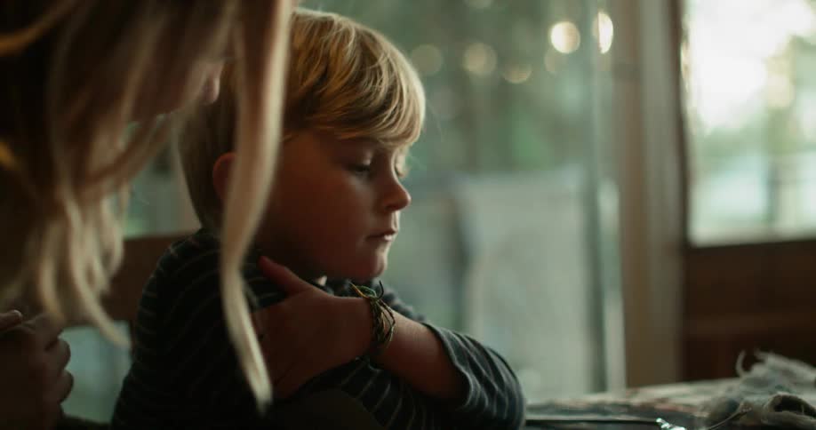 A woman rubs the back of a frustrated young boy