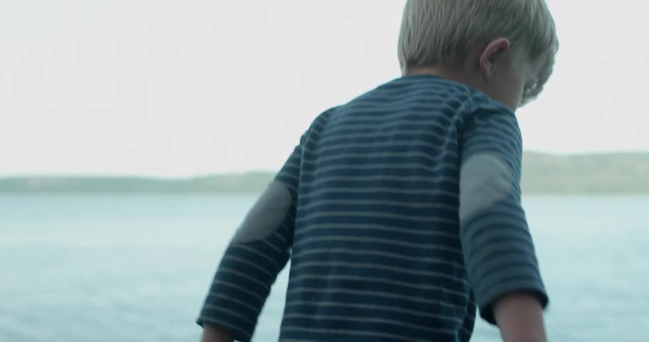 Boy climbs up a rock toward his dad