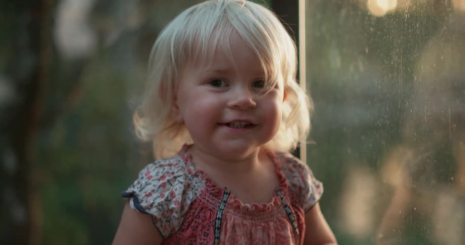 A young girl plays and runs near a window