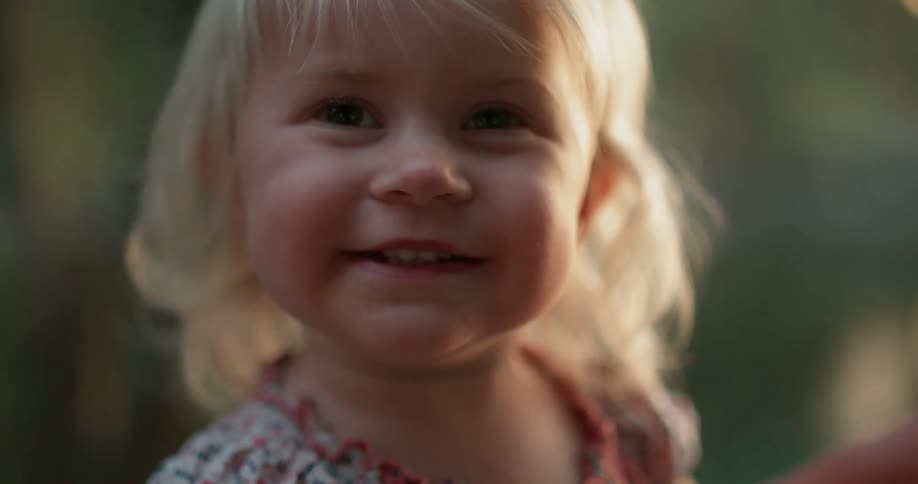 Smiling toddler girl smiling and then looking up towards the sky