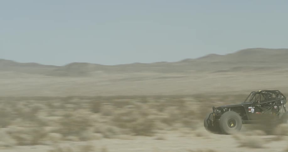 Dune buggy racing across a field on a clear day