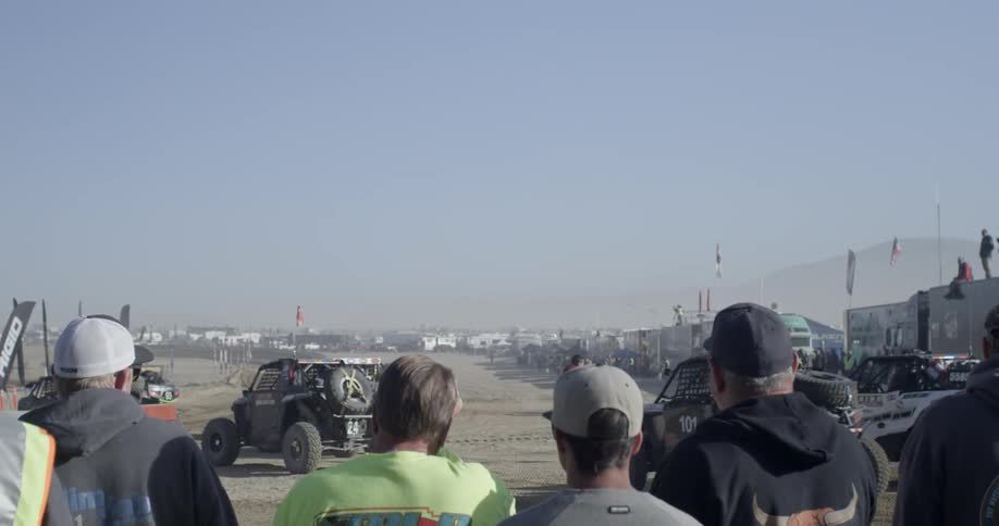People watch dune buggies head toward the track