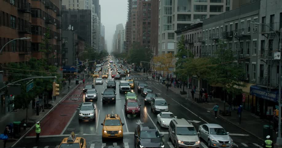 City street surrounded by tall buildings and teeming with cars