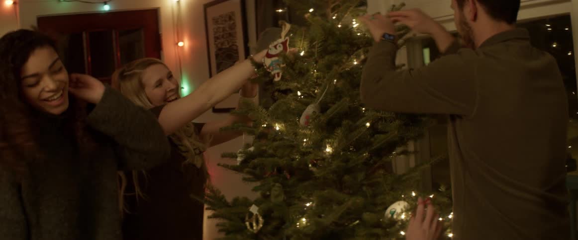 People are decorating a christmas tree