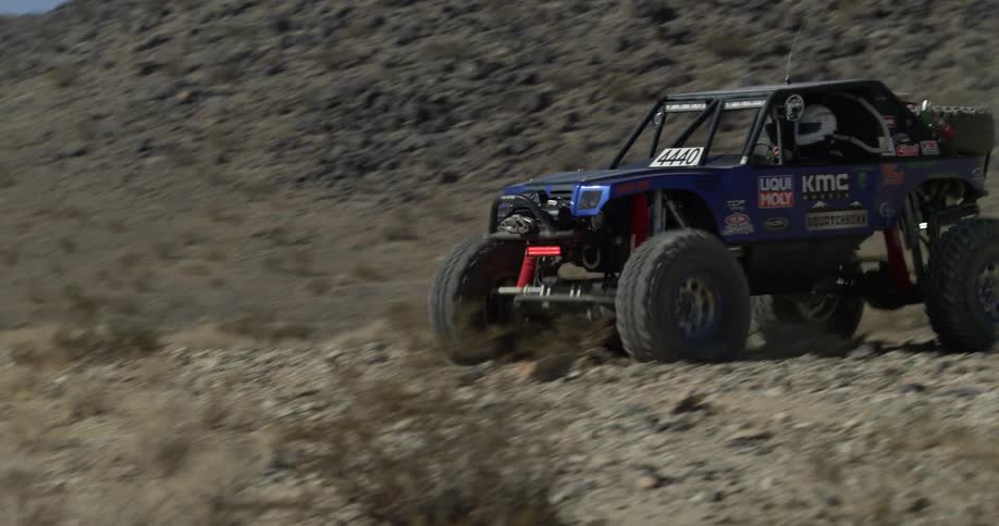 An off road vehicle drives and jumps up a hill