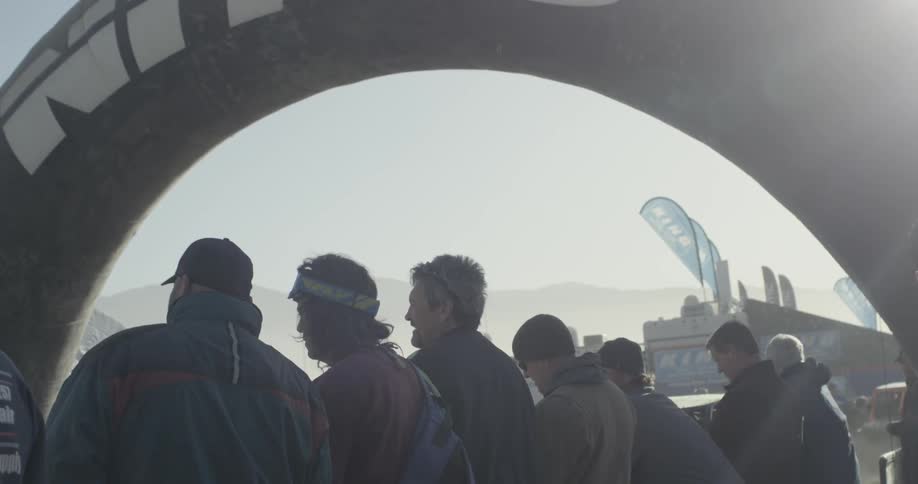 Spectators watch cars drive by on a sunny day
