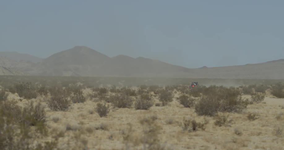 An off road vehicle drives through a desert