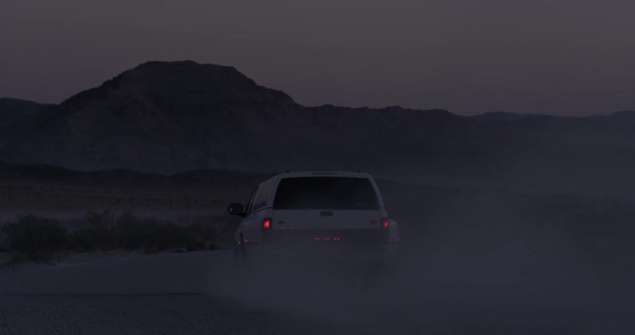 A truck travels through the desert kicking up sand