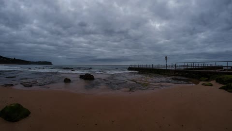 Dark clouds hover over a beach and boardwalk area