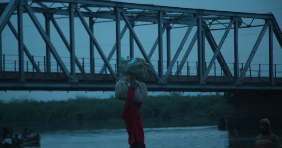 A man stacks bags on his head and carries them