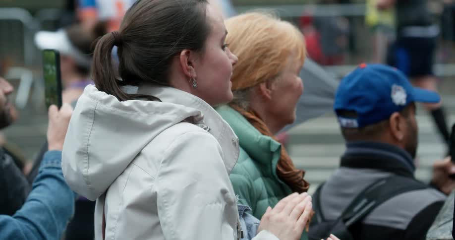 A woman is clapping as runners pass by