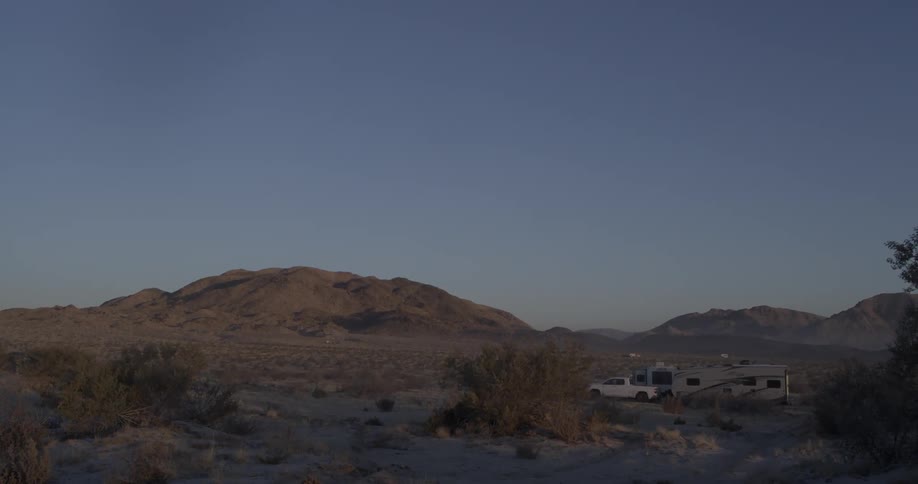 A pickup truck and trailers are parked in the dessert