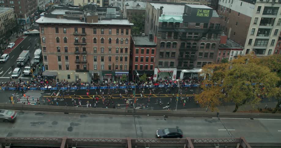 Cars pass on a bridge as marathon runners compete below