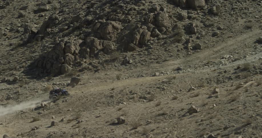 An off road vehicle travels up a dirt and rock hill