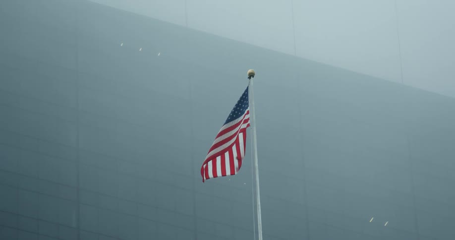 An american flag billows in the wind on a foggy day
