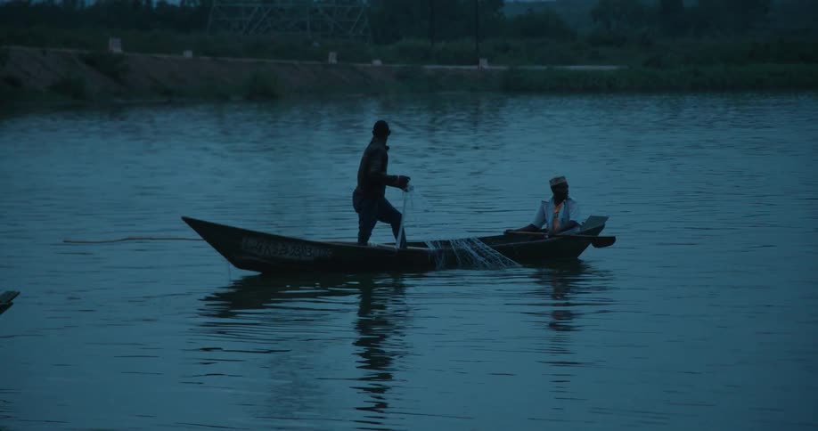 A man pulls netting from the water onto a boat