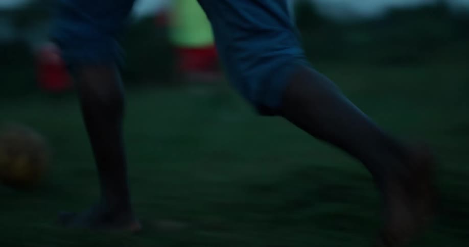 A group of children play soccer in the grass