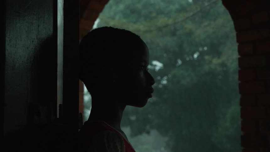 A boy stands in an archway during the rain