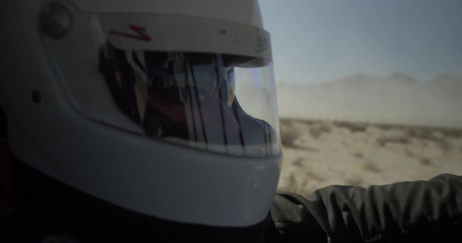 A man wears a helmet while driving an off road vehicle