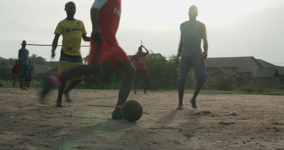 Boys play soccer on a dirt field