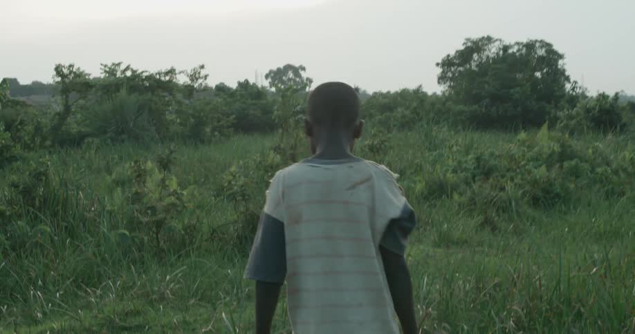 Boy walking outdoors in a grassy area on a cloudy day