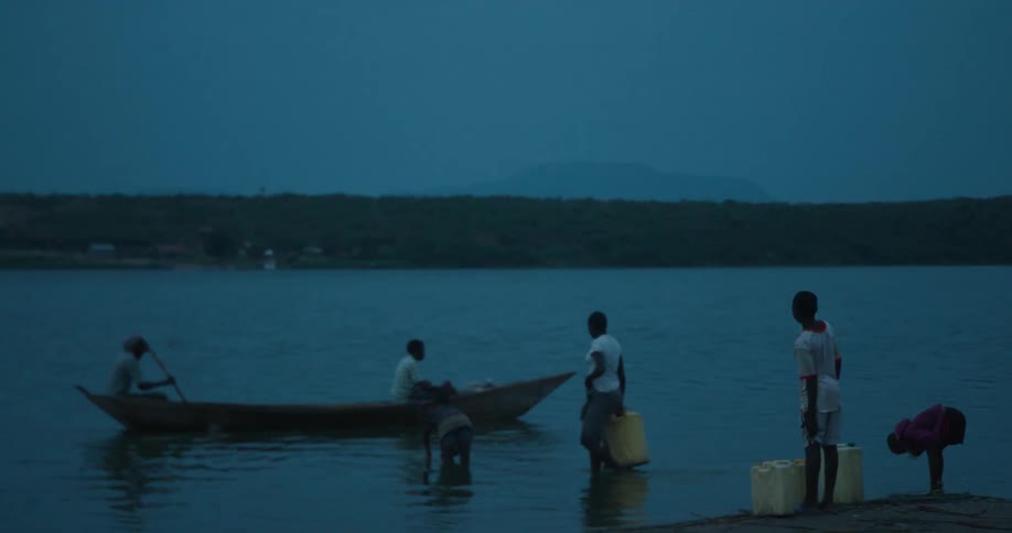 People wade in a river as a boat floats by
